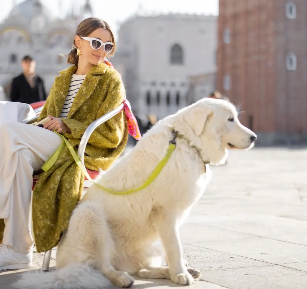 A woman sitting on a bench next to a white dog.