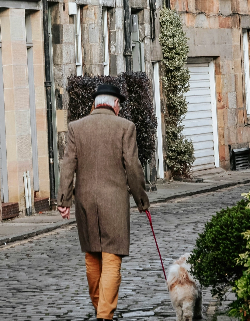 A man walking a dog down a cobblestone street.