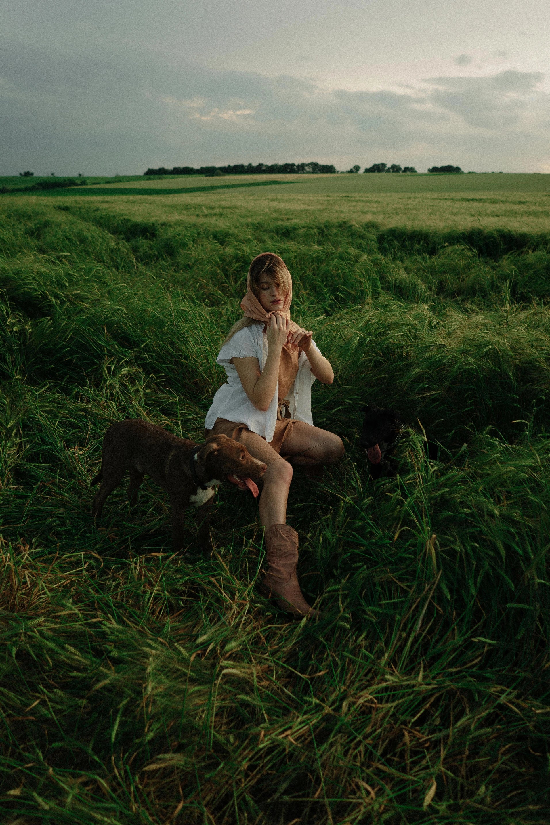 A woman sitting in a field with a dog.