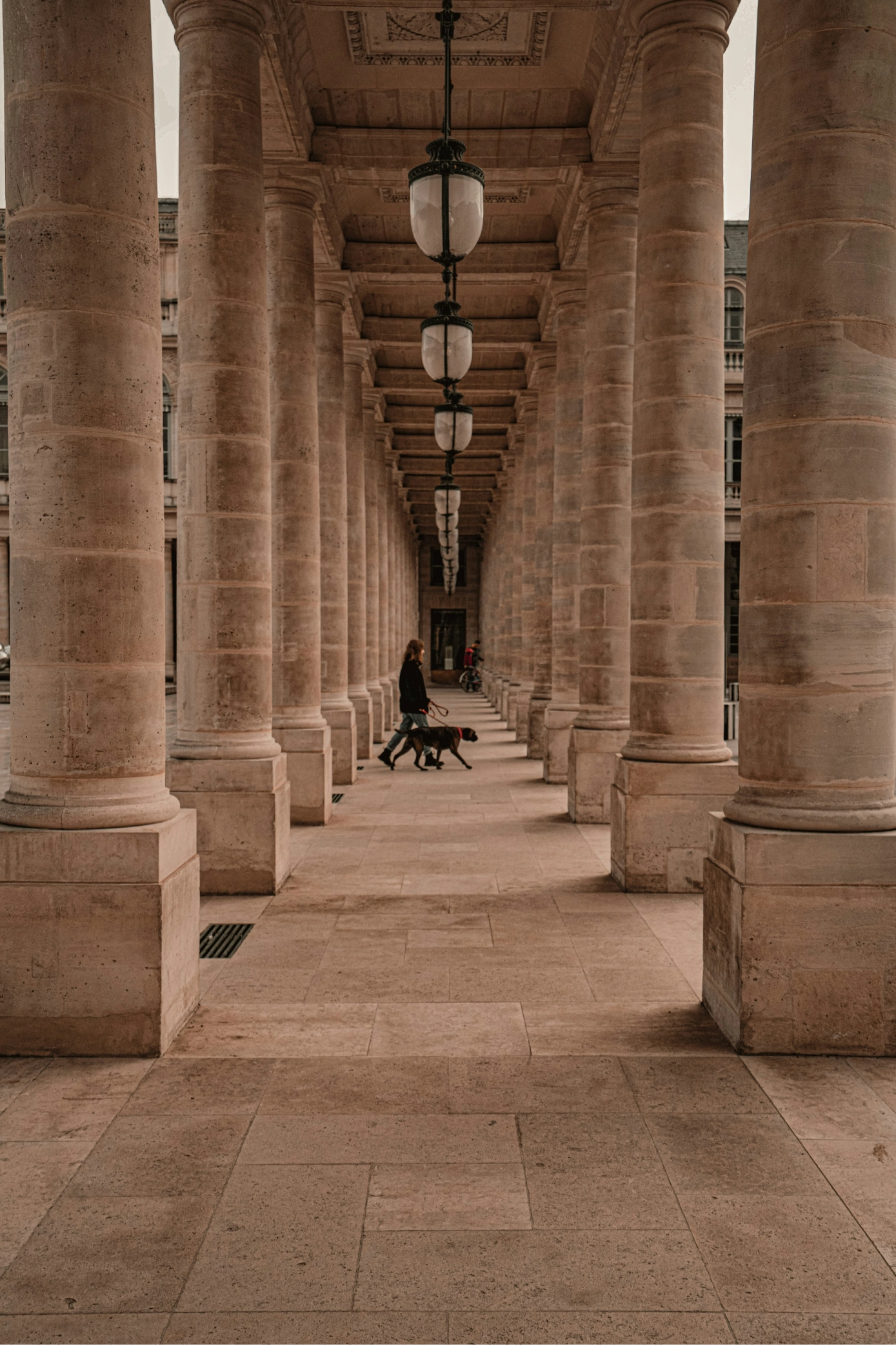 A person sitting on a bench under a covered walkway.